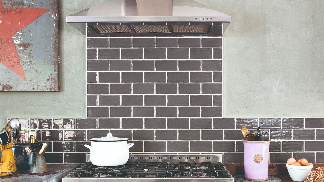 Kitchen with a large stove and extractor fan with a tiled backsplash