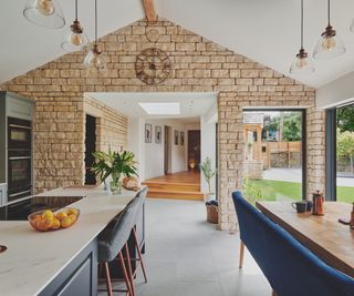 A classic kitchen open plan dining room with a large kitchen island with pendant lighting and light buff floor