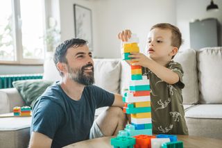 child playing with dad building bricks