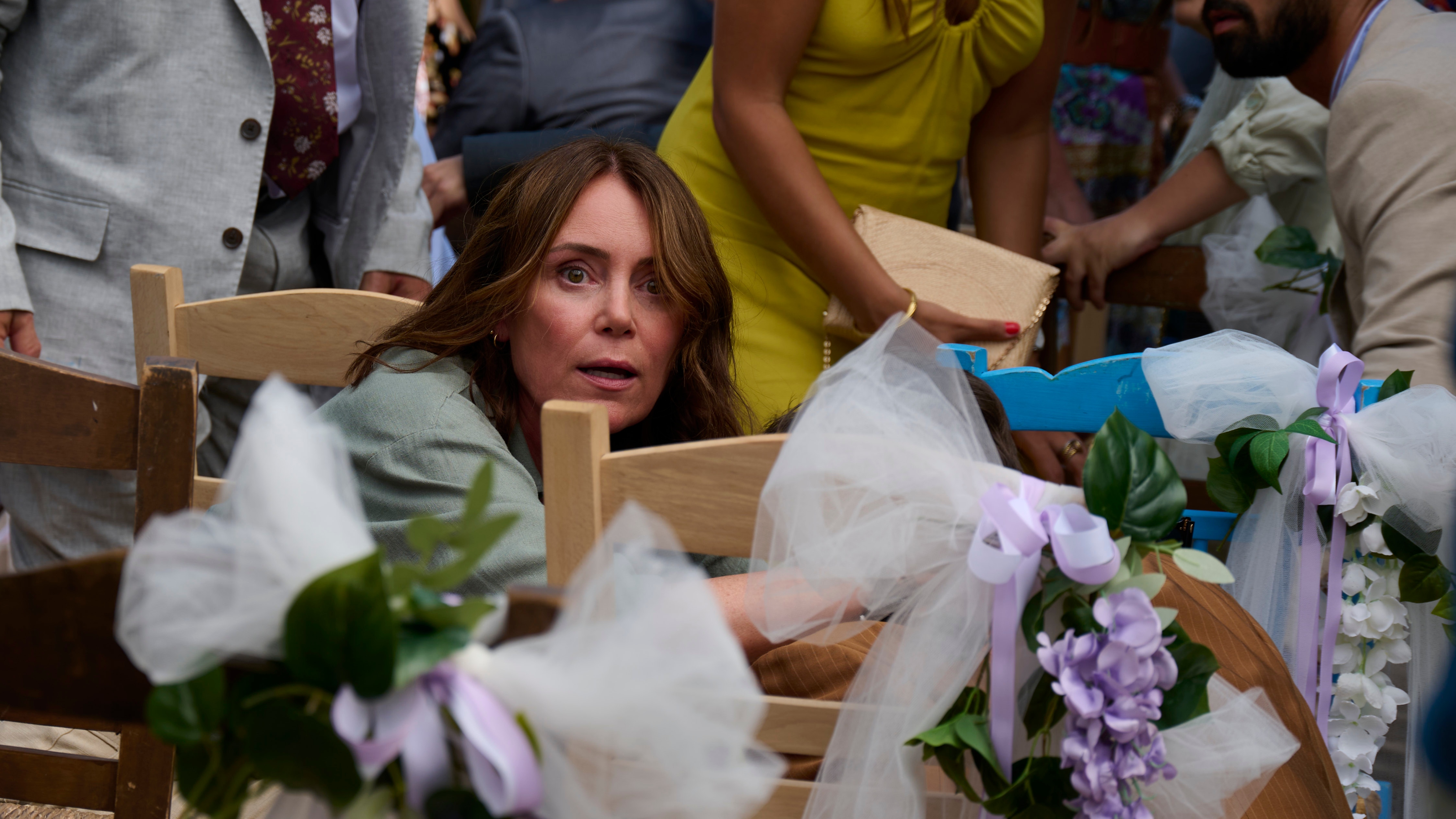 Julie ducks behind a chair with wedding flowers tied onto it in The Assassin