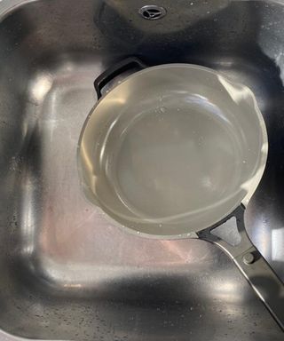 An Our Place Always pan rinsed clean with water in kitchen sink