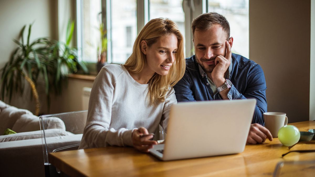 Couple sitting at table using a laptop