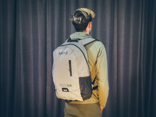 Will Jones, wearing one of the best backpacks for cycling, stands in front of a wall