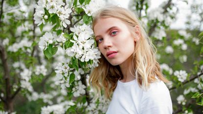 a woman posing next to flowers - vegan make-up