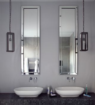 A bathroom with two mirrors, and long pendants hung on either sides