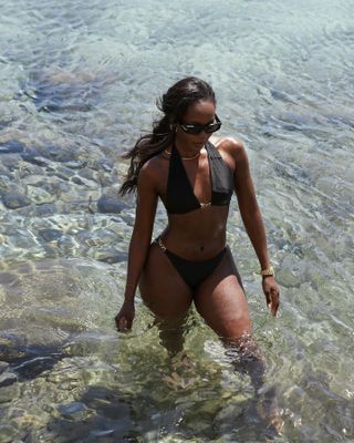 Woman standing in the water wearing a black bikini.