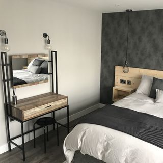 Bedroom with wall and ceiling lights, wooden headboard and grey feature wall