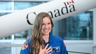 jenni gibbons with her hand on her chest. behind her is a canadarm model