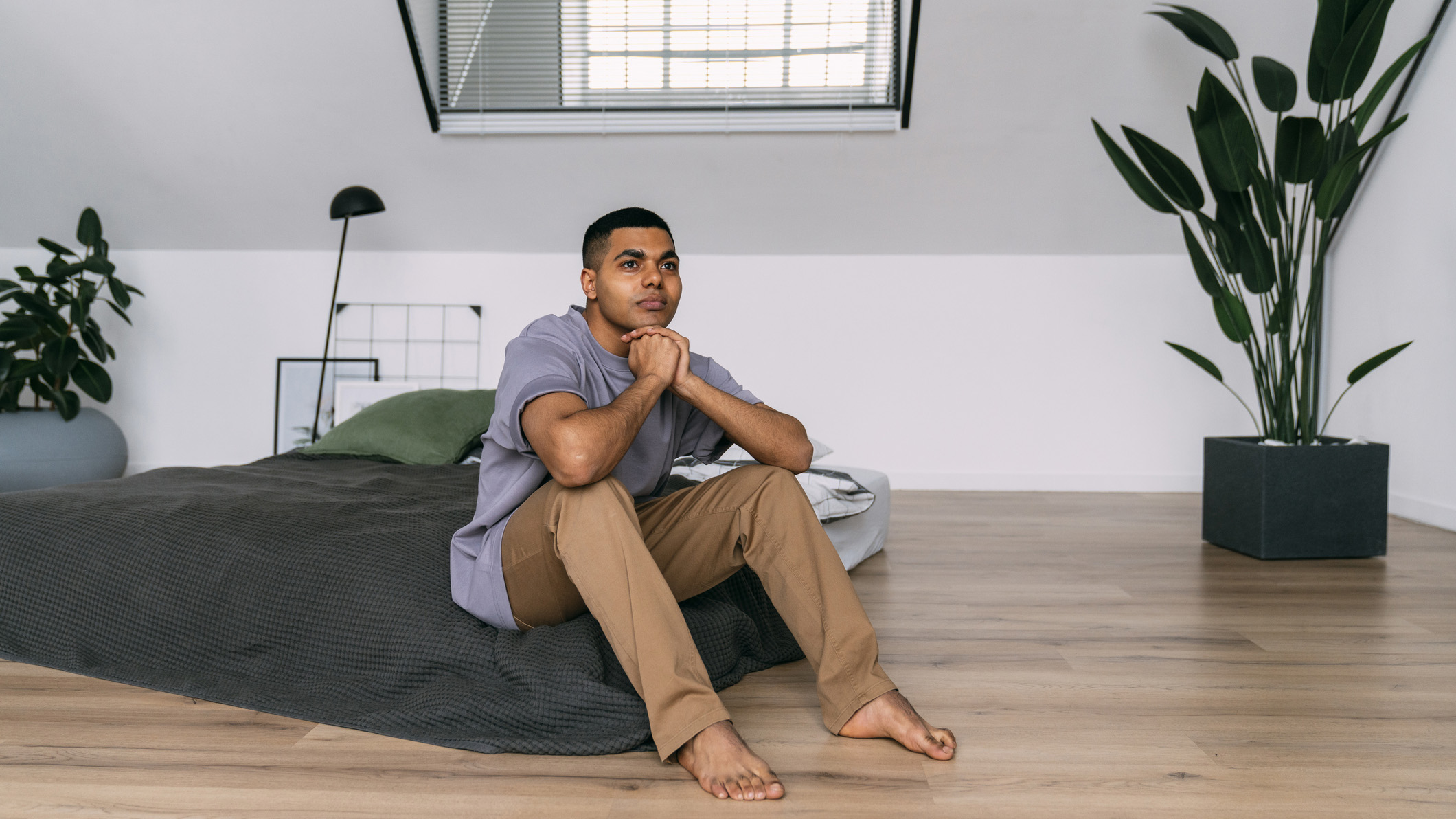 A man sits on a mattress on the floor
