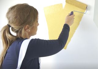 white wall with yellow paint dipped paint roller