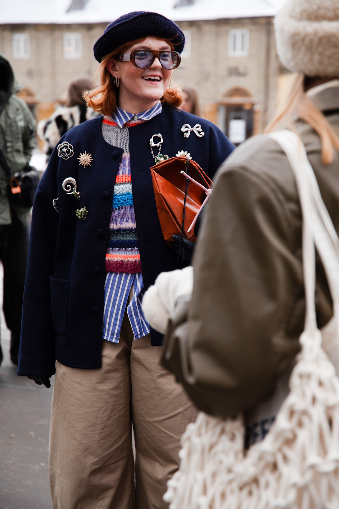 a guest at copenhagen fashion week wearing a coat covered in pins