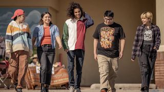A still from the TV shows Reservation Dogs showing all of the main teen characters walking together and smiling.