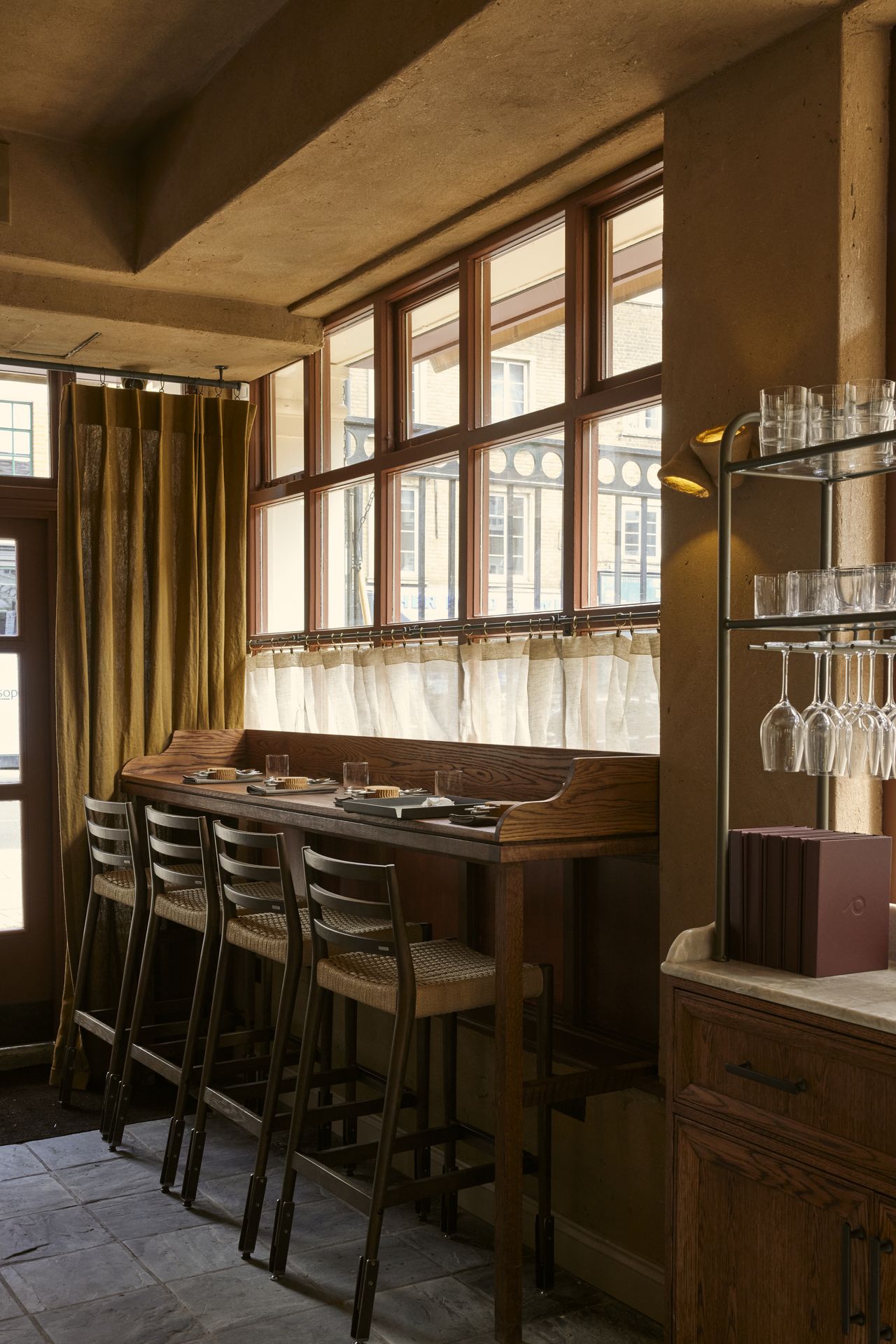 A series of handcrafted accessories, including ceramics and quirky table lamps, sit in a beautifully decorated restaurant filled with natural light.