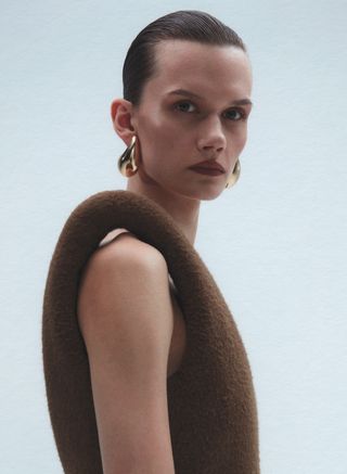 Close up of model in Bottega Veneta structured shoulder dress and earrings