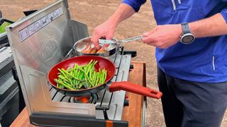 Person cooking on GSI Outdoors Pinnacle Pro 2 Burner Stove