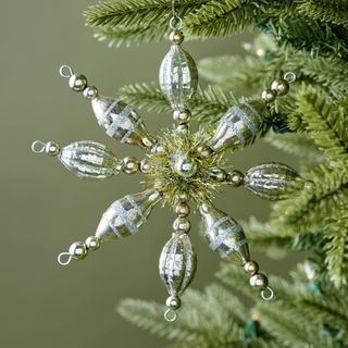 Vintage-Inspired Snowflake Ornament against a green background.