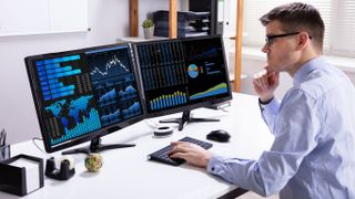 A picture of a man working on two monitors