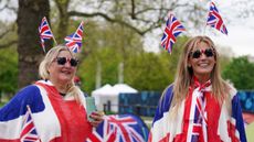Two women wear Union Jack themed clothing as they camp out along the Mall to secure their positions on the eve of the coronation