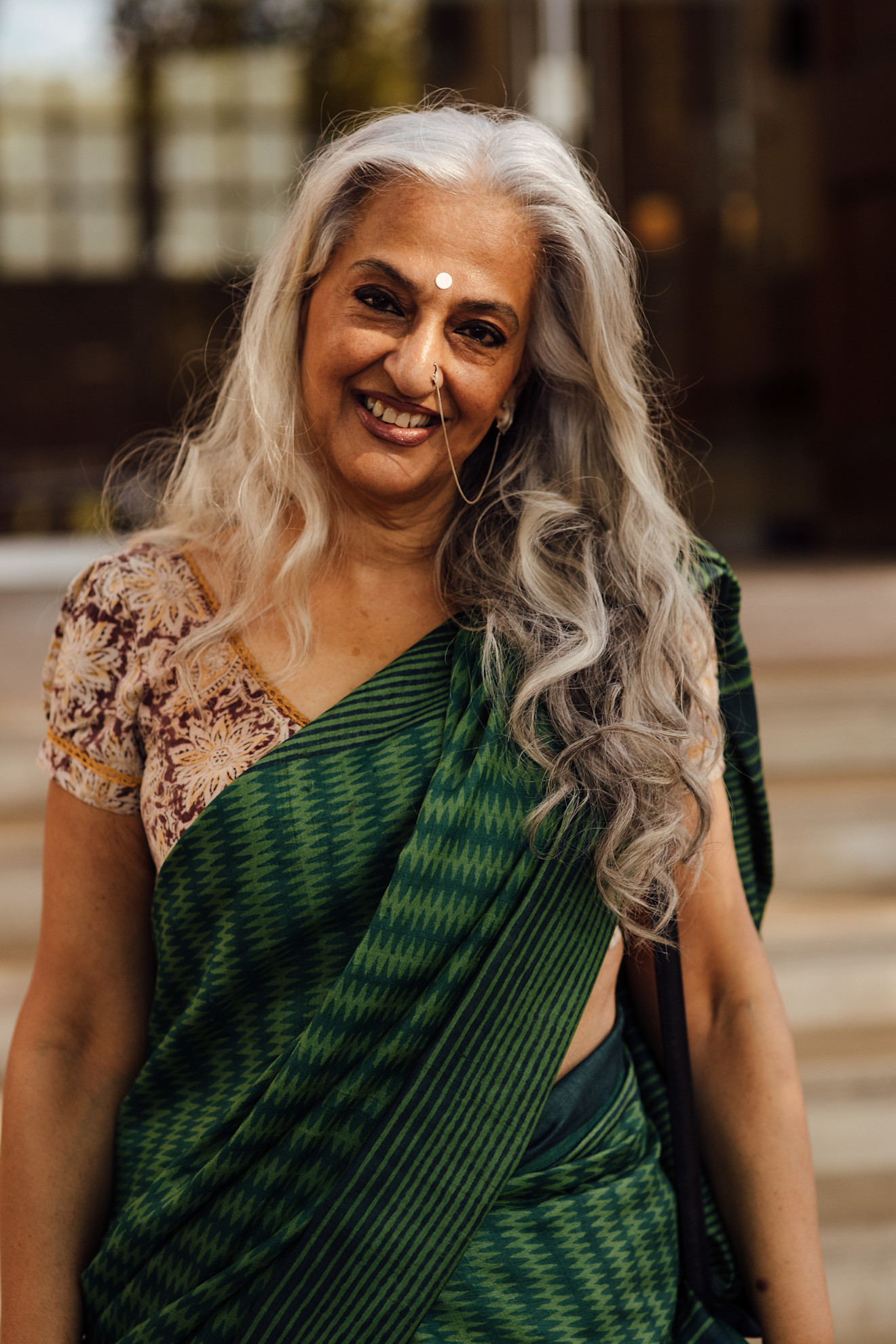 an older Indian woman in a green sari with long gray hair