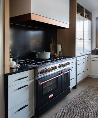 White kitchen with a black and copper range cooker framed by symmetrical drawers