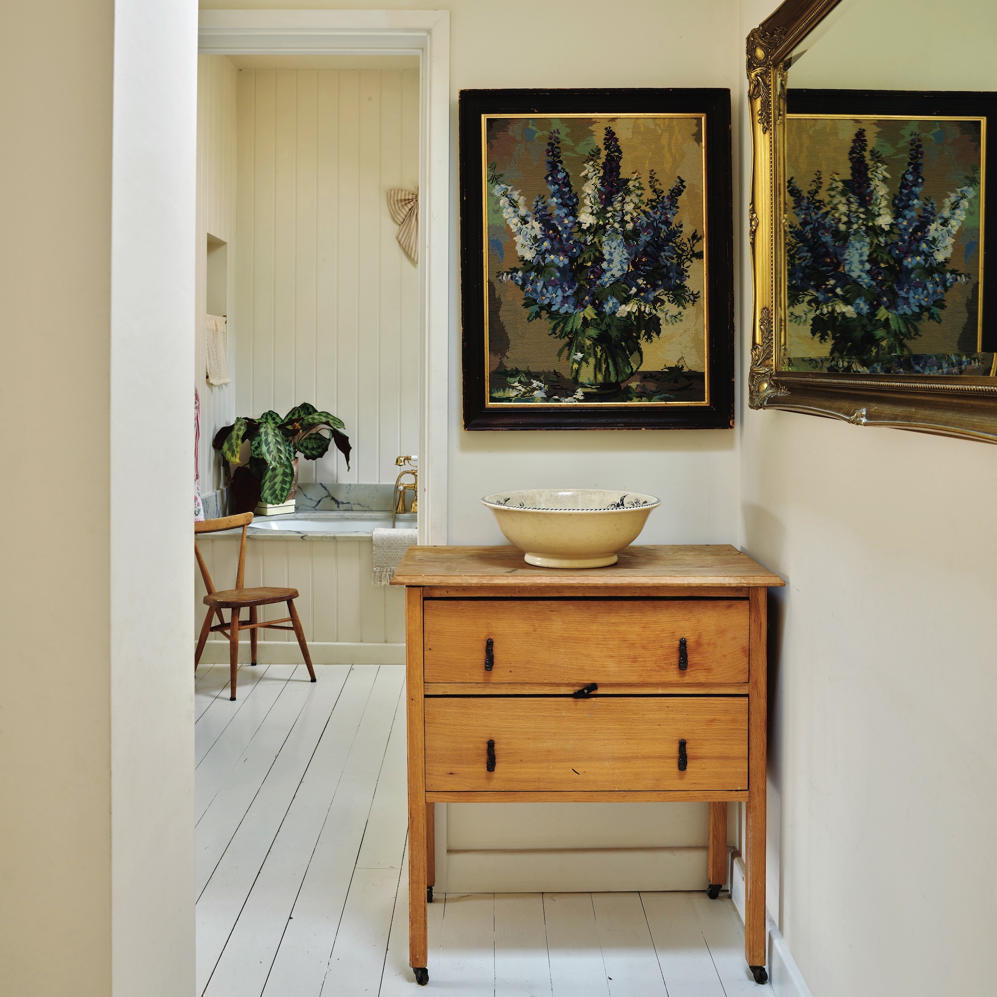 landing with small wooden chest of drawers, oil painting above and view to bathroom beyond