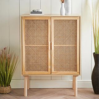 Sideboard made from MDF and real cane with solid wooden legs and rectangular handles in front of white wall