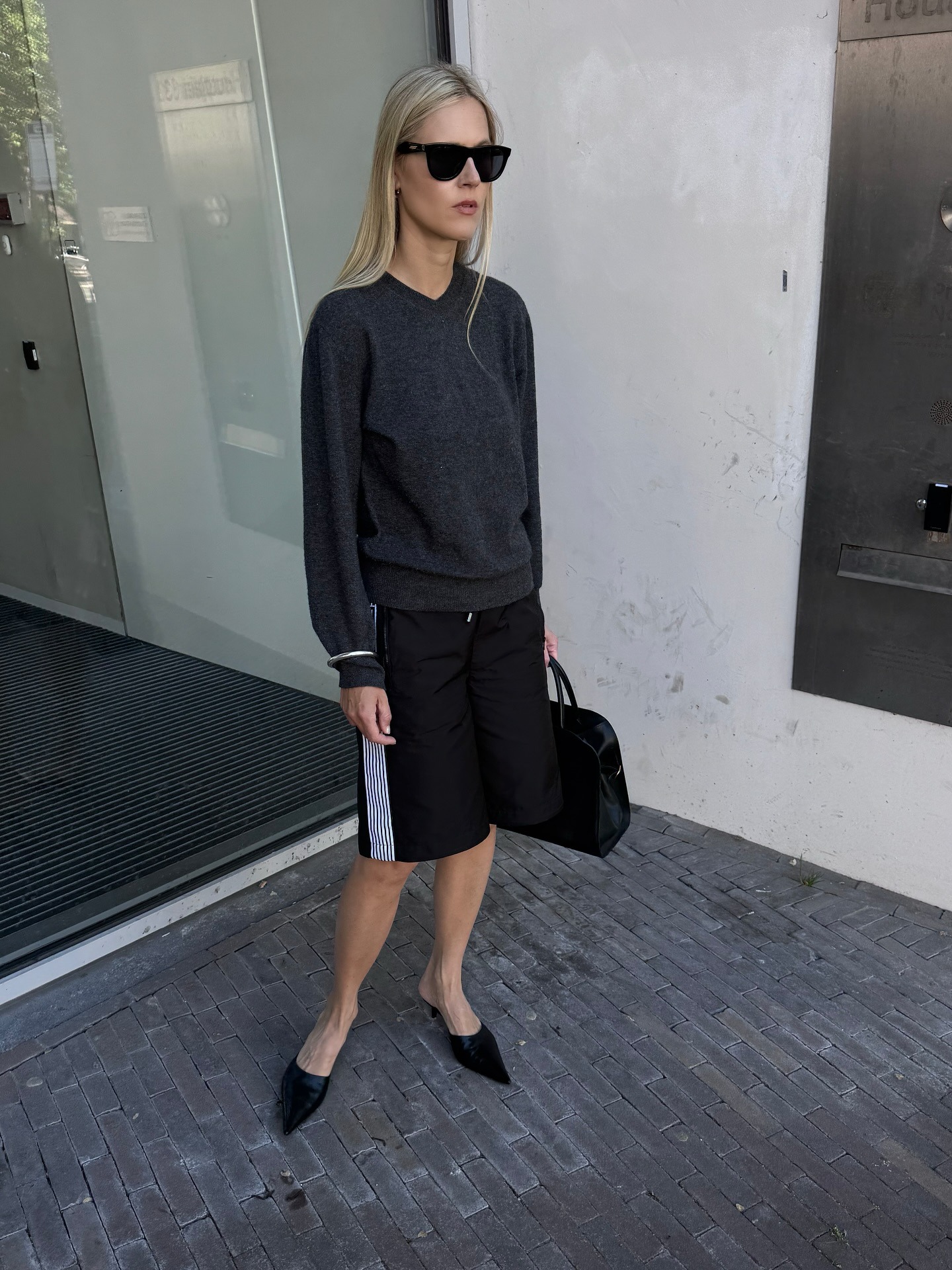 Influencer @lindatol_ wears long sports shorts with a grey jumper and pointed-toe heels.
