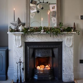 Marble fireplace lined with foliage and candles and a large mirror