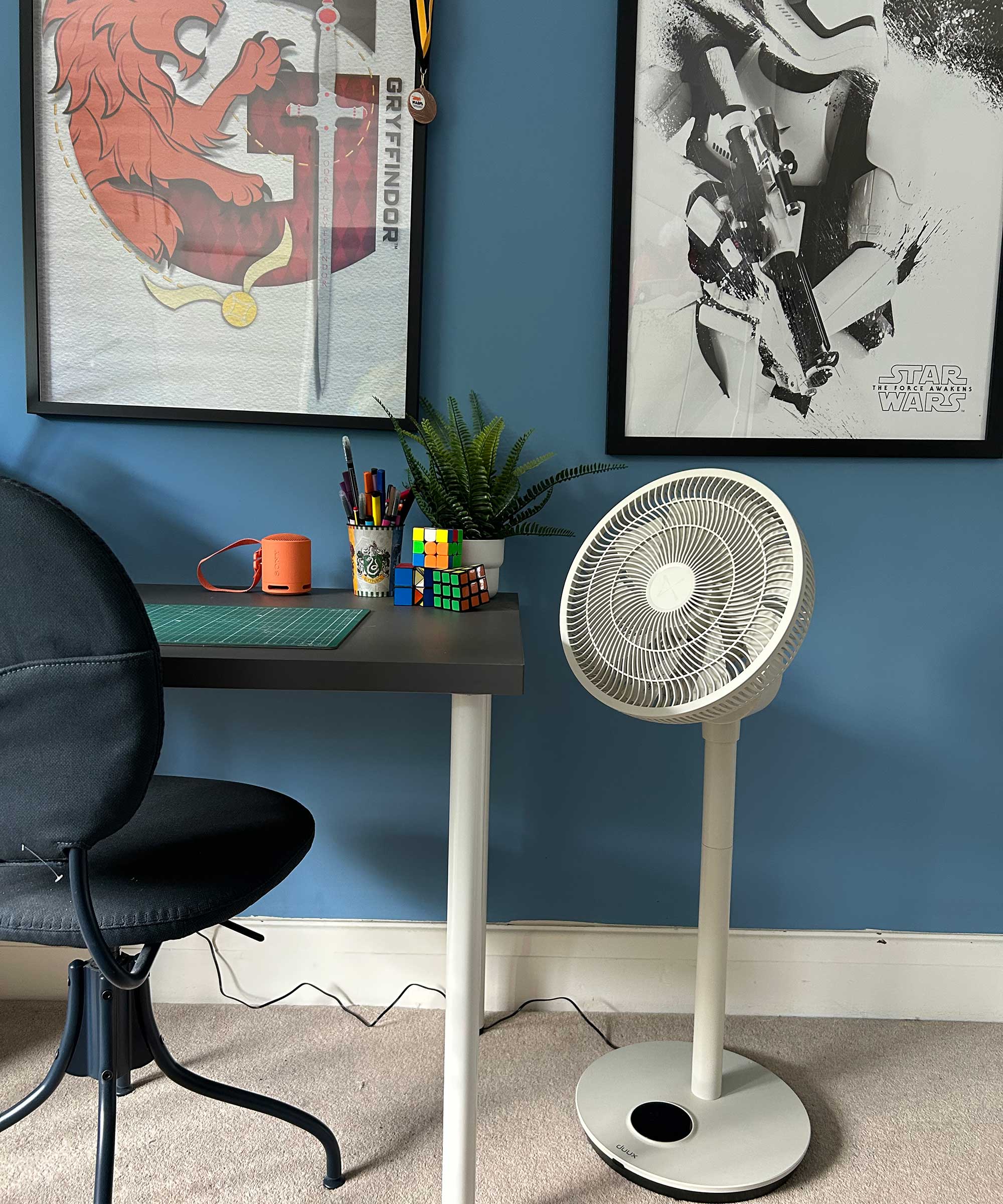 Duux Whisper Flex 2 fan next to a desk space in a child's bedroom with blue walls and art on the walls
