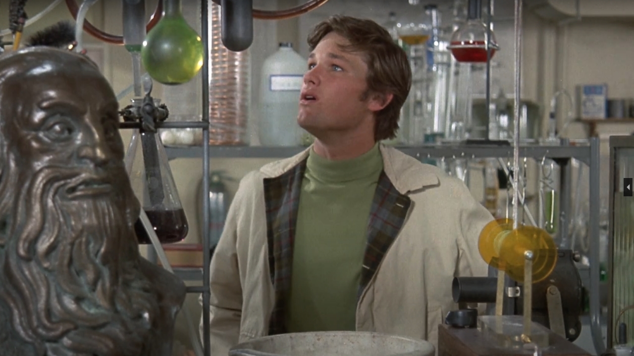 Kurt Russell looking at chemistry apparatus