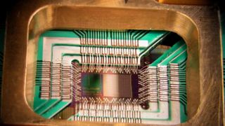 Photograph of a chip constructed by D-Wave Systems Inc., designed to operate as a 128-qubit superconducting adiabatic quantum optimization processor, mounted in a sample holder