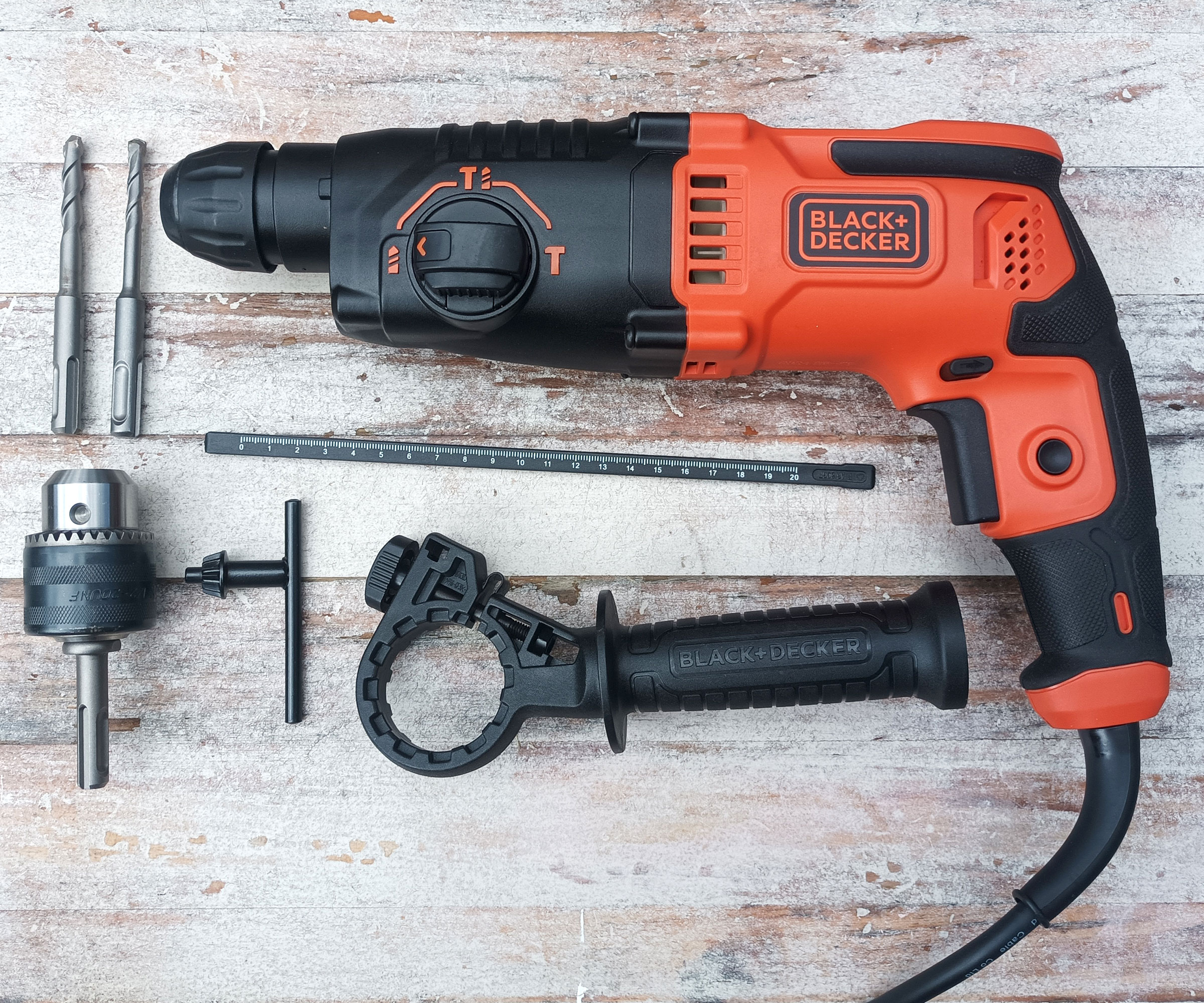 Top down shot of Black and Decker BEHS01 SDS Drill and parts on whitewashed wooden background