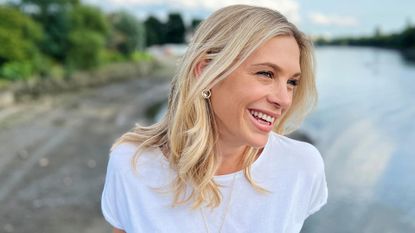 Chelsy Davy in a white t-shirt standing in front of water