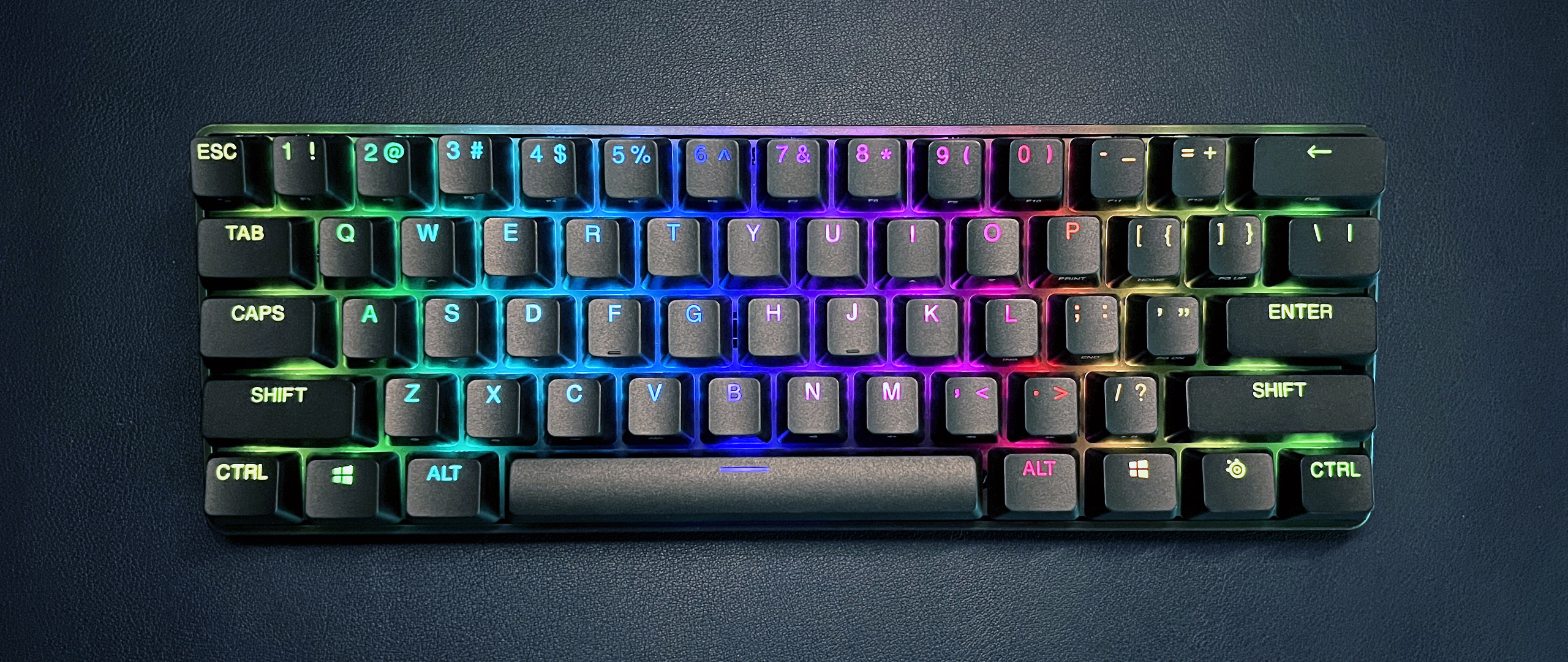 small black keyboard with rainbow lighting against dark blue background