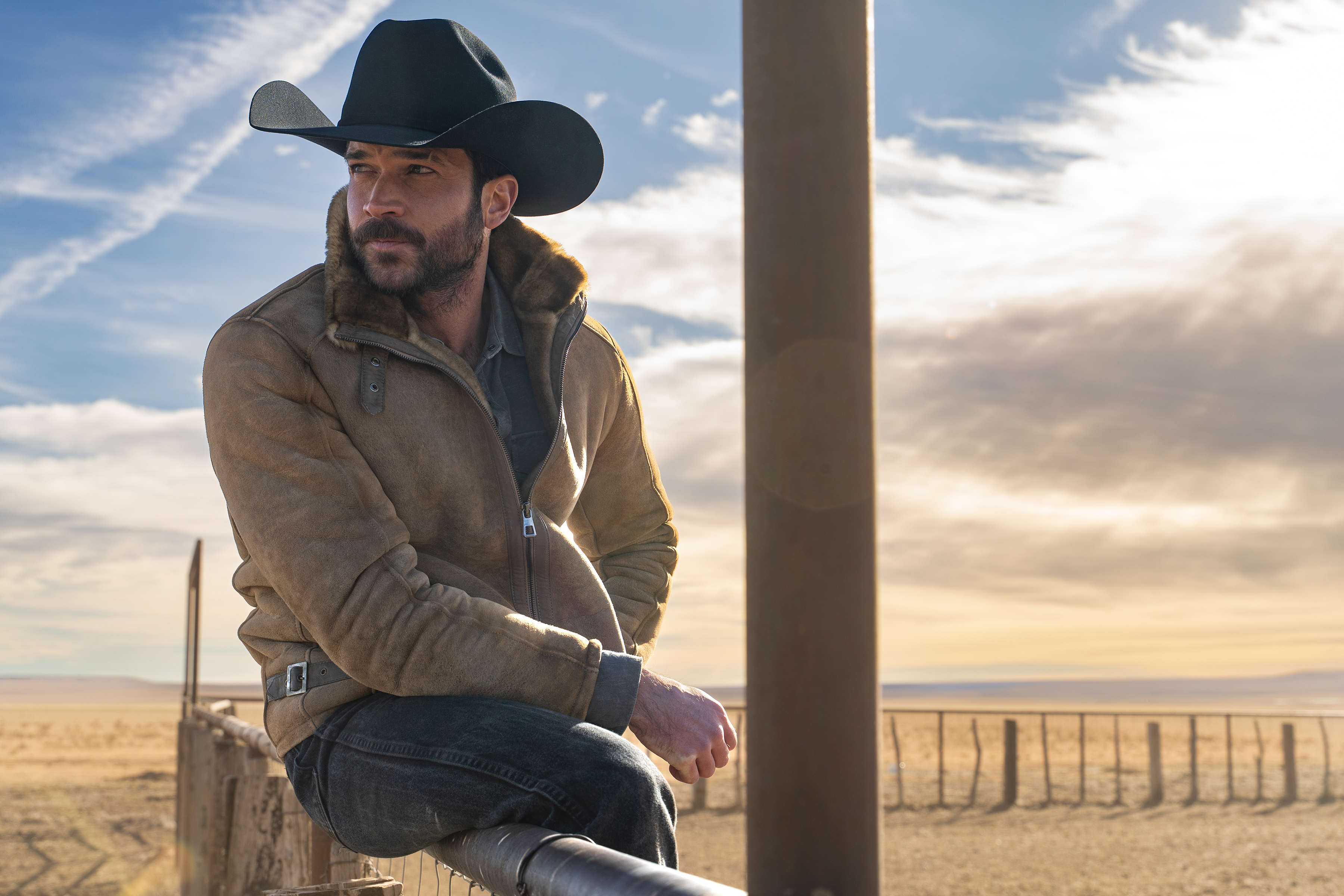 Jack Schumacher as Yancy wears a cowboy hat while sitting on a fence in Episode 207 of 'Ransom Canyon' Season 2.