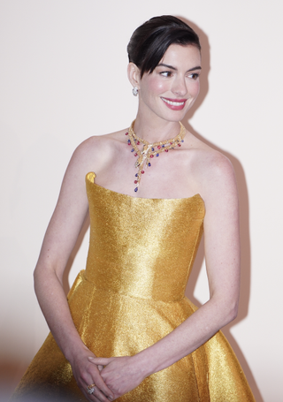 Actress Anne Hathaway attends the opening ceremony of Bvlgari Infinity Serpents Exhibition on January 8, 2025 in Shanghai, China in a gold midi dress