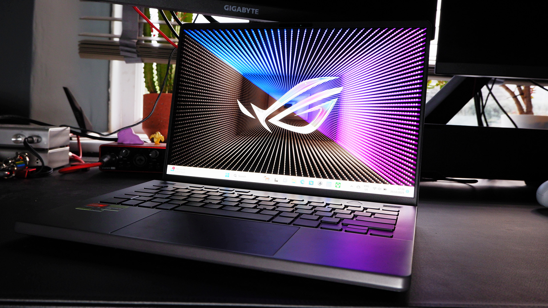 Asus Zephyrus G14 (2023) on a desktop with the Asus default background on-screen