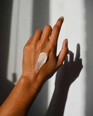 Image of a woman's hand with a swatch of hand cream on the back.