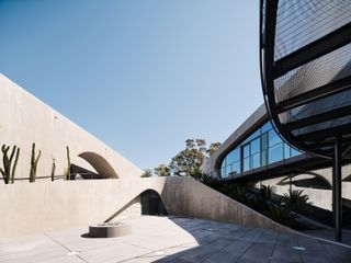 hill house montecito, flowing concrete house in the californian context with arid landscape and a tree around