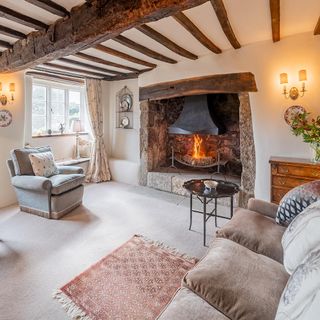 living area with wooden beam and fireplace and arm chair and white wall