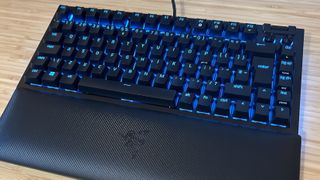Razer BlackWidow V4 75% with blue backlighting on a wooden desk