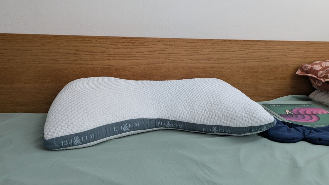 Eli and Elm Side Sleeper Pillow on the bed with a green bedsheet in a brightly lit room