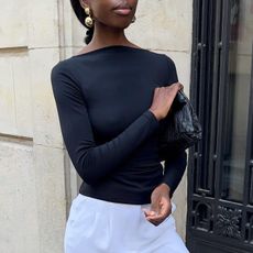 A woman wearing a black long sleeve top and white culotte pants 