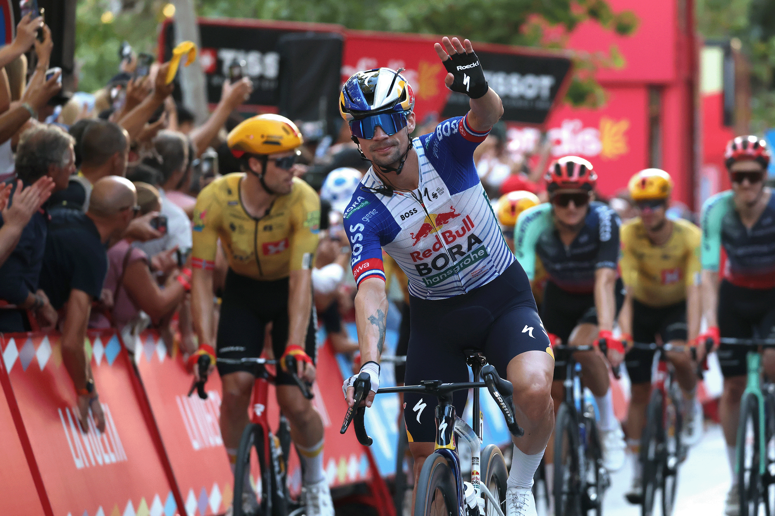 Primoz Roglic waves as he crosses the line