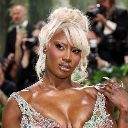 A woman, Aya Nakamura, with bleached blonde hair and rose blush on the 2024 met gala red carpet.