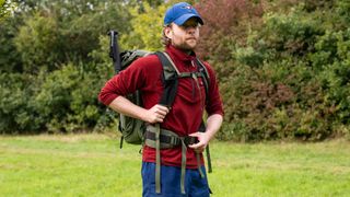 Man adjusting the straps of the PGYTech OnePro Focux Backpack in a green outdoor location