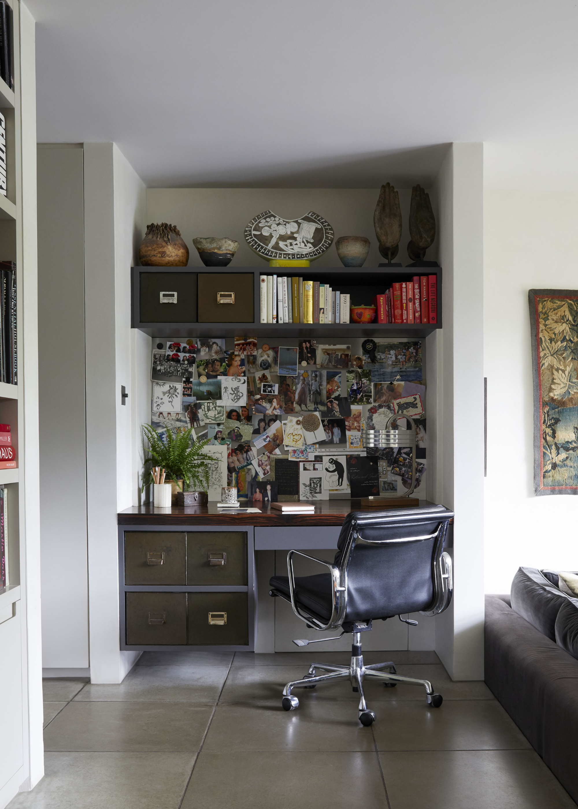 a small home office built into a recess of a wall covered in photos