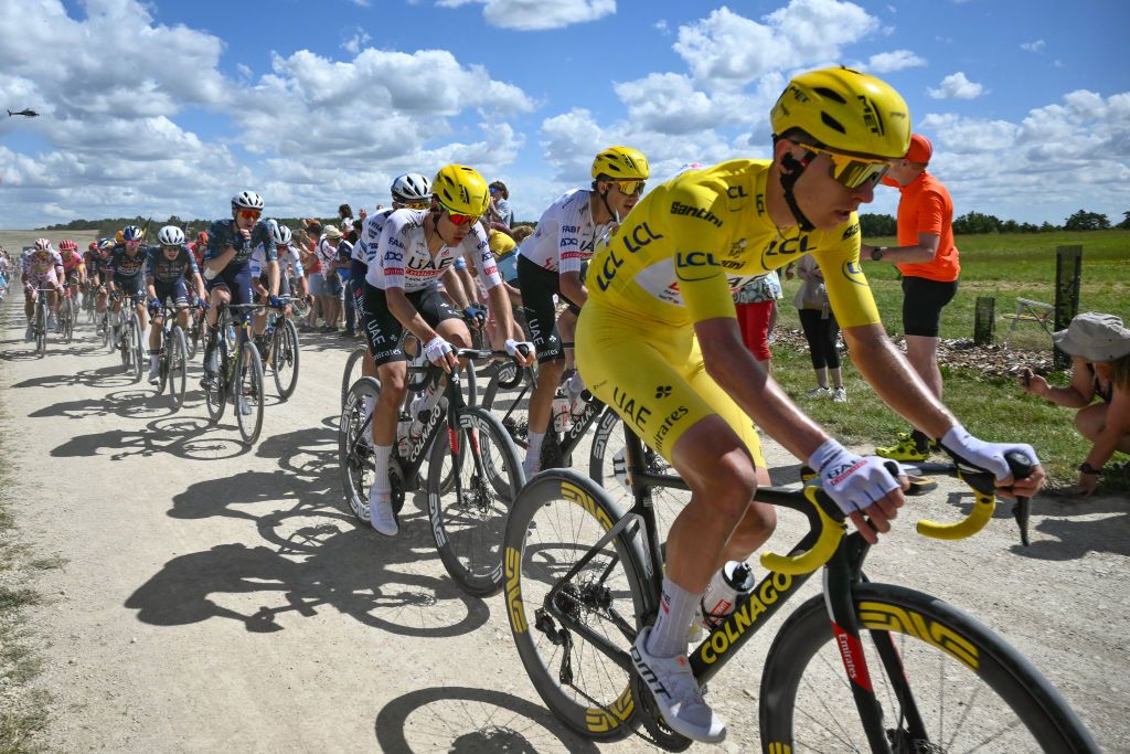 UAE Team Emirates team's Slovenian rider Tadej Pogacar wearing the overall leader's yellow jersey cycles with the pack of riders (peloton) over a "Chemin Blanc" (white road) gravel sector during the 9th stage of the 111th edition of the Tour de France cycling race, 199km stage departing and finishing in Troyes, on July 7, 2024. (Photo by Marco BERTORELLO / AFP)