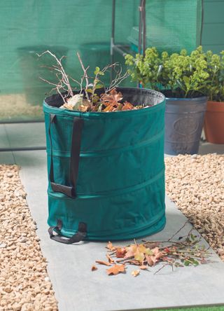 pop up outdoor garden bin in a gravel garden with twigs and leaves inside the bin