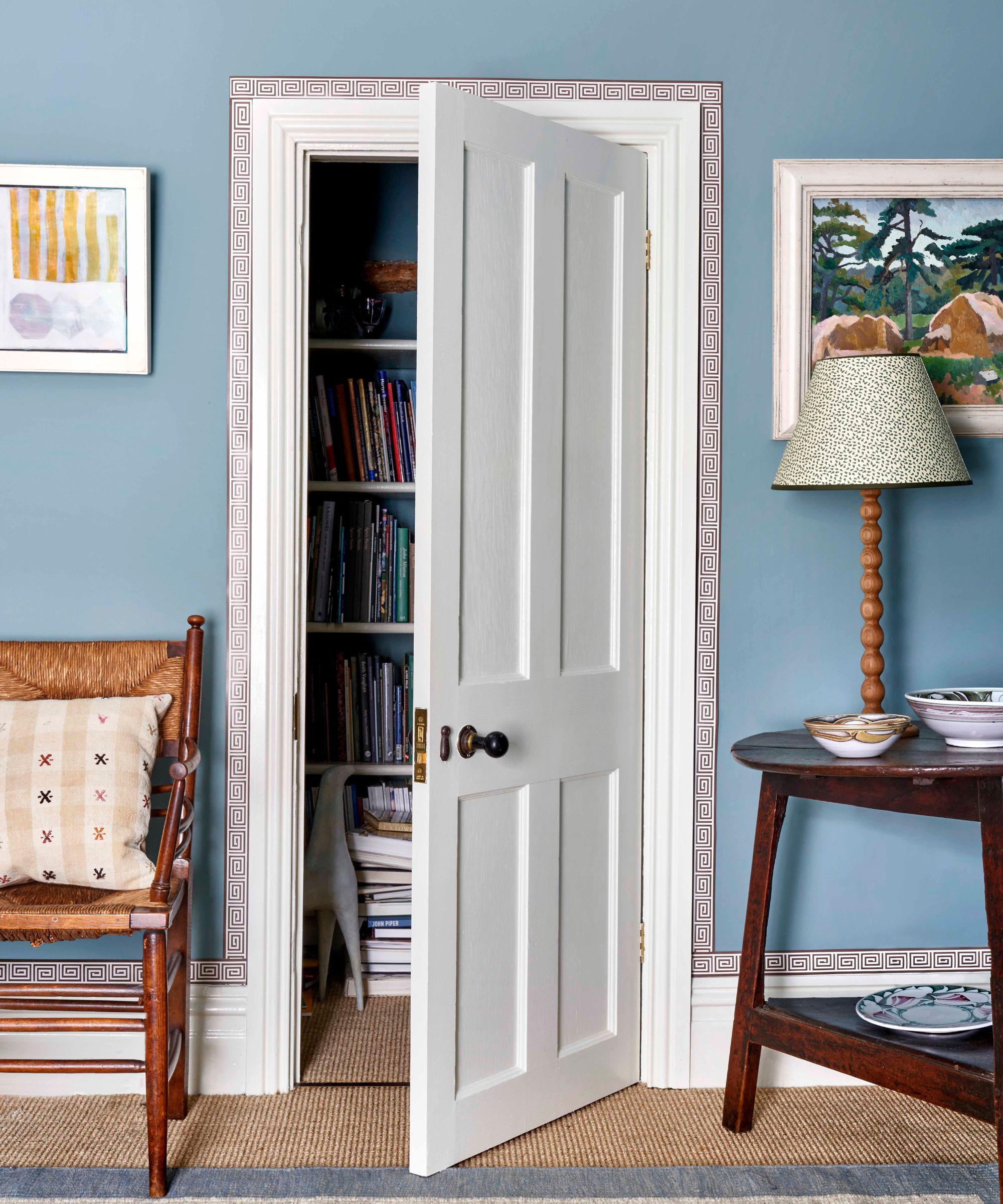 A white door partially ajar showing a storage closet. Blue painted wall with a small red and white border around the door frame.
